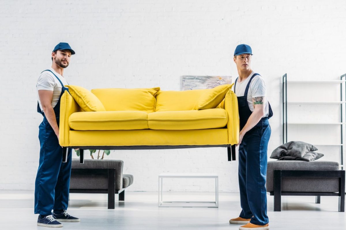 two-movers-in-uniform-transporting-couch-in-apartment.jpg